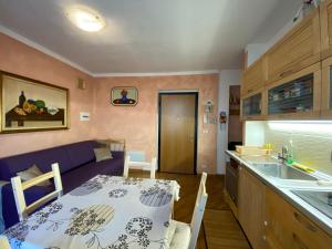 a kitchen and living room with a table and a purple couch at SARA'S in Bardonecchia