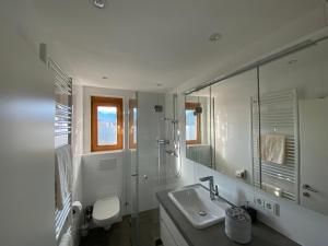 een witte badkamer met een wastafel en een douche bij Gemütliche Wohnung mit Gartenblick in Innsbruck