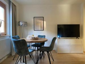 een eetkamer met een tafel en stoelen en een televisie bij Gemütliche Wohnung mit Gartenblick in Innsbruck