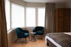 um quarto com 2 cadeiras, uma cama e janelas em B&B Maaltebrug em Gent