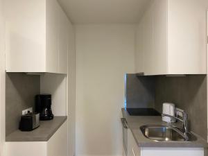 een keuken met witte kasten en een wastafel bij Gemütliche Wohnung mit Gartenblick in Innsbruck