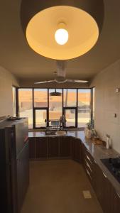 a kitchen with a large yellow light on the ceiling at Sand House ساند هاوس in Al Raka