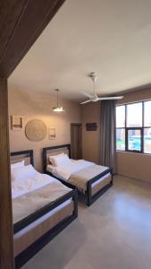 a bedroom with two beds and a large window at Sand House ساند هاوس in Al Raka
