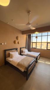 a bedroom with two beds and a large window at Sand House ساند هاوس in Al Raka