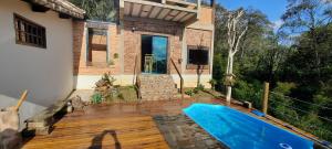 a house with a swimming pool on a wooden deck at Casa Refúgio da Paz - 2 quartos, 10 pessoas in Conceição da Ibitipoca