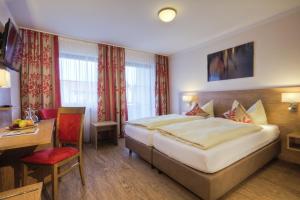 ein Hotelzimmer mit einem großen Bett und einem Schreibtisch in der Unterkunft Thermenhotel Ströbinger Hof in Bad Endorf