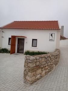 a white house with a stone wall in front of it at casinha do corvo in Fátima