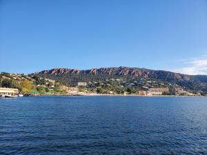a large body of water with a mountain in the background at Village Cap Estérel Agay St Raphaël vue mer et piscine in Agay - Saint Raphael