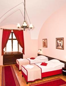 three beds in a room with a red rug at Hotel Klastrom in Győr