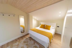 a bedroom with a large white bed with yellow pillows at Apartamentos San Lazaro in Santiago de Compostela