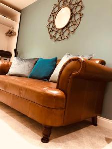 a brown leather couch in a living room with a mirror at Hideaway between Coast and Moors in a beautiful Village apartment in Sleights