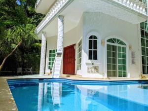 a pool in front of a house with a red door at 18br up to 50guest Castillos Playacar walk to Beach and 5th Ave 1000Mbps in Playa del Carmen