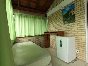 a room with a bed and a small refrigerator at Paraíso Hostel Praia do Rosa in Praia do Rosa