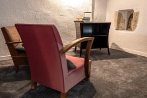 Orcet的住宿－Maison Georges Couthon，一张红色椅子,位于带书桌的房间