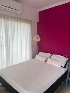 1 dormitorio con 1 cama grande y pared de color rosa en dithju en Tigre