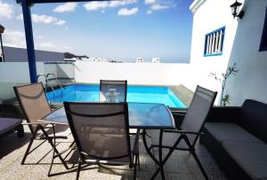 a patio with a glass table and chairs and a swimming pool at apartamentoscasajulia in La Santa