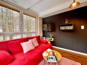un divano rosso in un soggiorno con finestra di Apartament SPA 04 Resort Kozubnik blisko Szczyrk - 5D Apartamenty a Porąbka