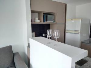 dos copas de vino sentadas en un mostrador blanco en una cocina en Hermoso departamento zona Guemes en Mar del Plata