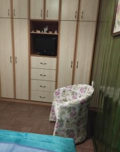 a bedroom with a chair and a tv and cabinets at Casa D' Irene in Karpenisi