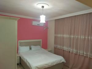 a bedroom with a white bed and a pink wall at YAFA Furnished Apartments Trabzon in Trabzon