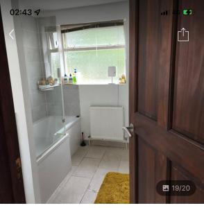 baño con bañera, lavabo y ventana en Bramcote 3 bedroom house, en Bramcote