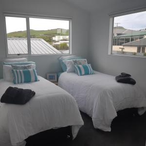 two beds in a room with two windows at Riverton Cottage 2 Bedroom Close to beach in Riverton