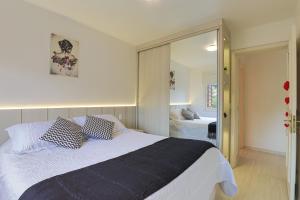 1 dormitorio con 1 cama grande y espejo en Conforto perto do centro, en Gramado
