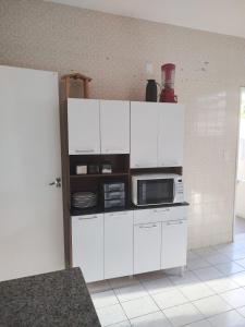 a kitchen with white cabinets and a microwave at Maré Hostel Itapuã in Salvador