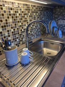 a kitchen sink with two mugs on a rack at Vakantiestudio Ouanaïo in Zedelgem