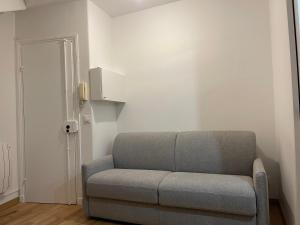ein graues Sofa in einem Zimmer mit Tür in der Unterkunft Chambre à Saint-Mandé entièrement refait à neuf in Saint-Mandé