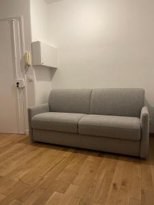 ein Sofa im Wohnzimmer mit Holzboden in der Unterkunft Chambre à Saint-Mandé entièrement refait à neuf in Saint-Mandé