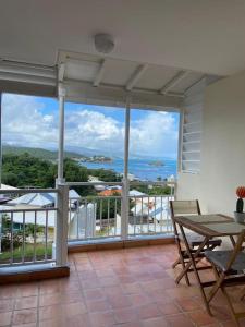 a balcony with a table and a view of the ocean at Studio au soleil levant, avec piscine in La Trinité