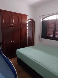 a bedroom with a bed and a wooden cabinet at Casa de Praia em Praia Grande (SP) in Solemar