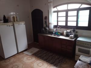 a kitchen with a white refrigerator and a sink at Casa de Praia em Praia Grande (SP) in Solemar