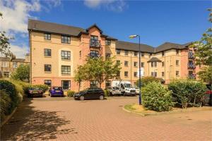 un gran edificio de ladrillo con coches aparcados en un aparcamiento en Modern Two Bedroom Apartment, Roseburn, Edinburgh - Free Parking, en Edimburgo