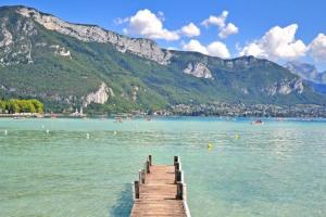 a wooden pier in the water with mountains in the background at T1 Proche Annecy in Épagny