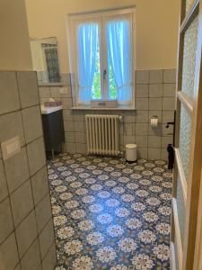 een badkamer met een tegelvloer, een raam en een wastafel bij MANZONI37 in Novi Ligure