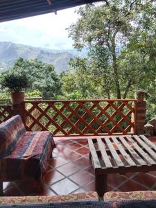 een houten bank op een patio met uitzicht bij Hospedaje rural - Finca la Aurora - Caqueza in Cáqueza