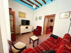 Casa Béjar, Tranquila casa con chimenea, patios, junto a la piscina في Cañete la Real: غرفة معيشة مع أريكة وتلفزيون
