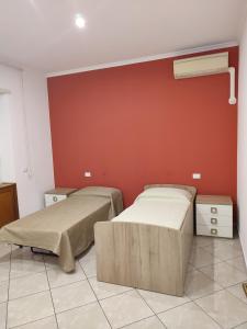dwa łóżka w pokoju z czerwoną ścianą w obiekcie Anna Roma House w Rzymie