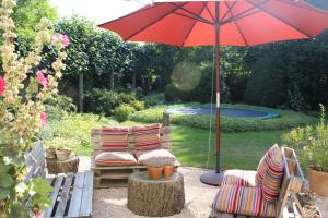 a patio with two chairs and a red umbrella at Authentieke privé-kamer bij Karen in Beveren