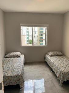 a room with two beds and a window at VISTA para o MAR!!! in Balneário Camboriú