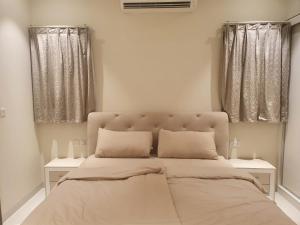 a bedroom with a large bed with two windows at Forest Island apartment in Salalah in Salalah