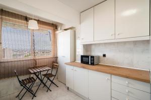 cocina con armarios blancos, mesa y ventana en MODERN AND BRIGHT APARTMENT Plaza Elíptica -MAGIN, en Madrid