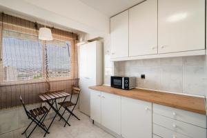 a kitchen with white cabinets and a table and a window at MODERN AND BRIGHT APARTMENT Plaza Elíptica -MAGIN in Madrid