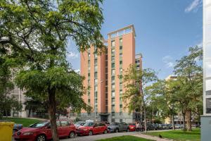 a tall orange building with cars parked in front of it at MODERN AND BRIGHT APARTMENT Plaza Elíptica -MAGIN in Madrid