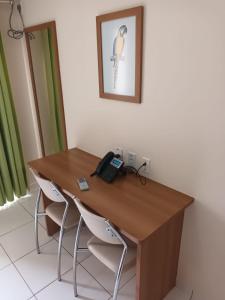 escritorio de madera con 2 sillas y teléfono en Suíte Grand Hotel Dolphin, en Caldas Novas