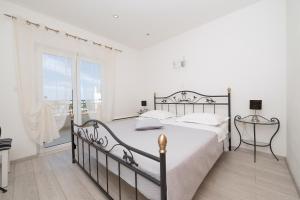 a white bedroom with a bed and a large window at Apartments Talija in Drasnice