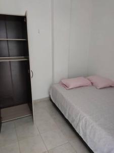 ein Schlafzimmer mit einem Bett mit rosa Kissen darauf in der Unterkunft Apartamento Arboletes a 2 cuadras playa principal in Arboletes