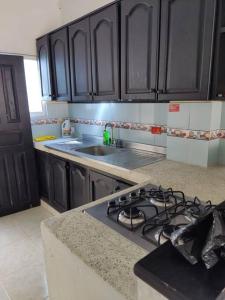 a kitchen with black cabinets and a stove top oven at Apartamento Arboletes a 2 cuadras playa principal in Arboletes